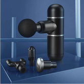 Compact black mini fascia gun massage device with four interchangeable massage heads on blue background