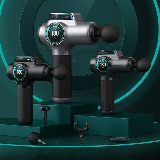 Three gray and black massage guns with LCD screens and multiple attachments displayed on green platforms for muscle relaxation and pain relief.